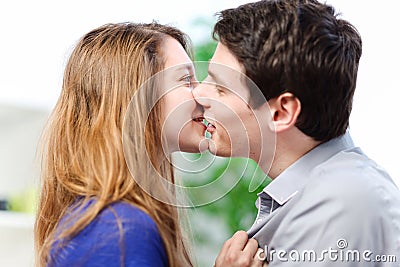 Attractive couple of lovers kissing itself lovingly on a sofa