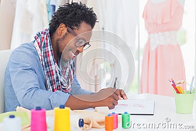 Attractive fashion designer sitting at his desk drawing