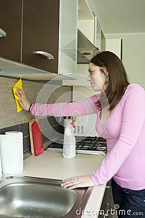Attractive girl polishing furniture on the kitchen