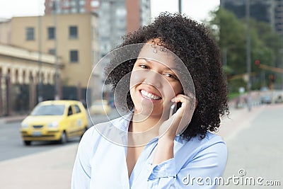 Attractive hispanic woman in the city calling a taxi