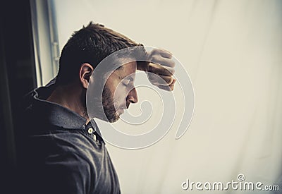 Attractive man leaning on window suffering emotional crisis and depression