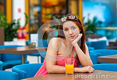 Attractive teen girl drinking juice in bar