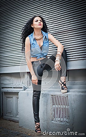 Attractive woman in black leather pants and shirt posing on the street