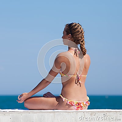Attractive woman in swimwear doing yoga at the sea