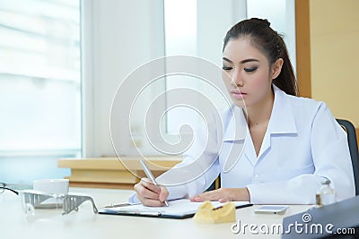 Attractive young female doctor sitting at desk in office