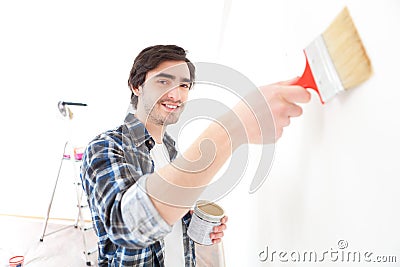 Attractive young man painting a wall in his new flat