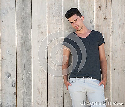 Attractive young man posing outdoors against wooden wall