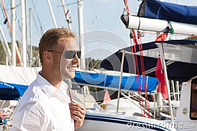 Attractive young man at seaport in front of sailing boat.