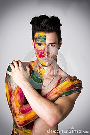 Attractive young man shirtless, skin painted all over with colors