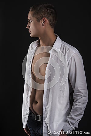 Sensual young man in white shirt standing in profile