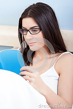Attractive young woman reading in bed