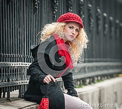 Attractive young woman in a winter fashion shot. Beautiful young girl with red umbrella in the street