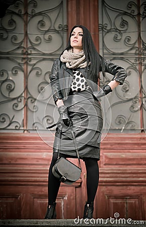 Attractive young woman in winter fashion shot with wrought iron decorated doors in background. Beautiful fashionable female