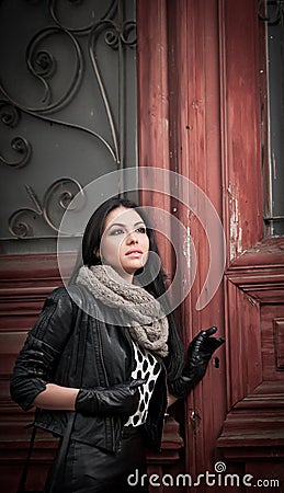 Attractive young woman in winter fashion shot with wrought iron decorated doors in background. Beautiful fashionable female