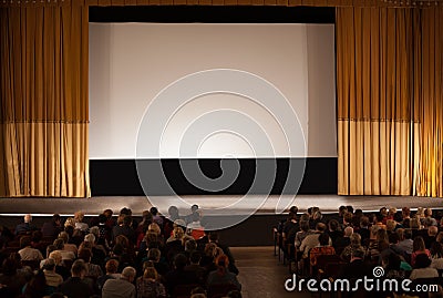 Audience in an auditorium in front of white cinema screen