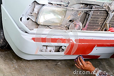 Auto mechanic preparing the front bumper of a car for painting