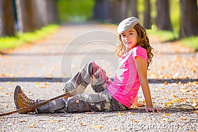 Autumn kid girl with camouflage pants sitting in trees track