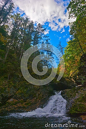 Autumn landscape with a waterfall on the creek taiga.