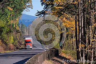 Autumn road with beautiful scenery and red semi truck