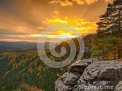 Autumn sunset view over sandstone rocks to fall colorful valley of Bohemian Switzerland. Sandstone peaks in forest.