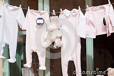 Baby clothing and teddy bear in window