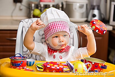 Baby cook girl wearing chef hat in kitchen.