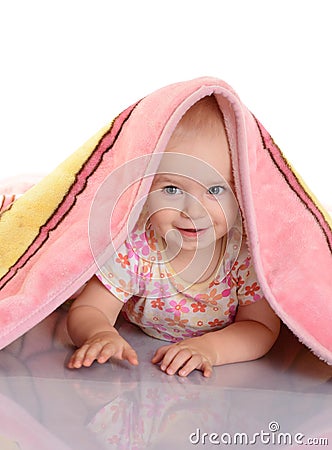 Baby girl is hiding under the blanket over white background