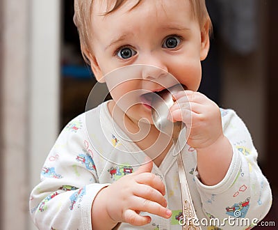 Baby girl holding spoon in mouth