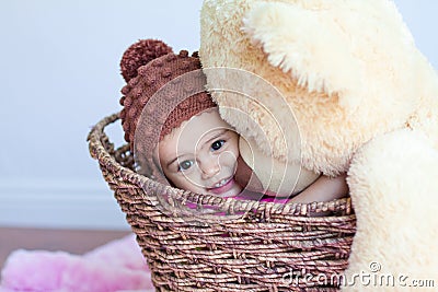 Baby girl hugging big teddy bear in basket