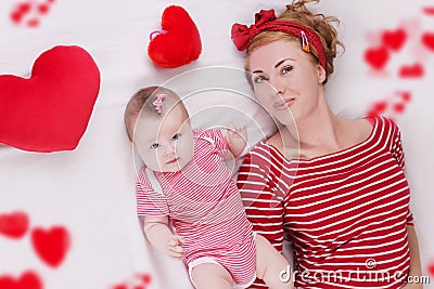Baby girl and mother lying among plush hearts