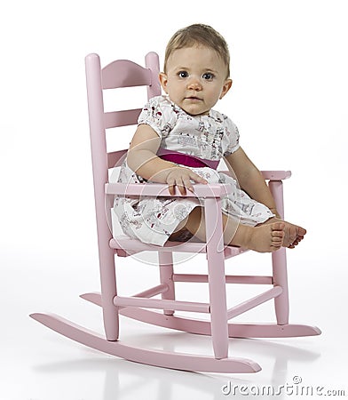 Cute baby girl in pink rocking chair, white studio background.