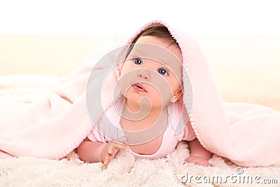 Baby girl under hidden pink blanket on white fur