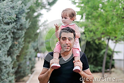 Baby girl walking on the shoulders of her father