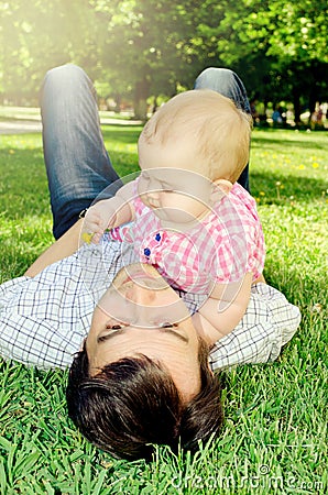 The baby lies on the grass with her dad