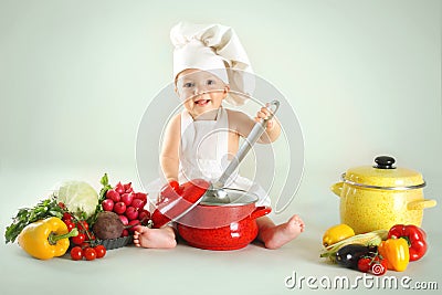Baby wearing a chef hat with vegetables and pan