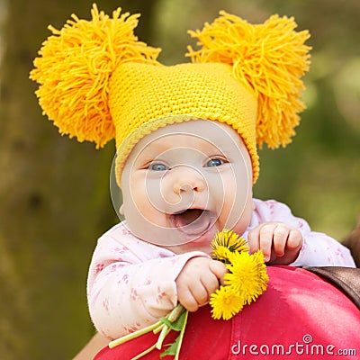 Baby in yellow knitted cap with dandelions