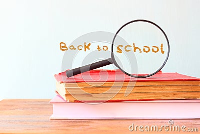 Back to school background with stack of books and magnifying glass