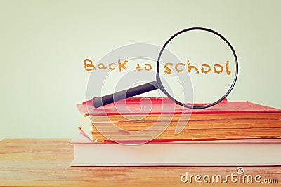 Back to school background with stack of books and magnifying glass. filtered image