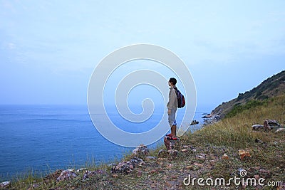 Backpack man standing on rock mountain and looking to ocean use