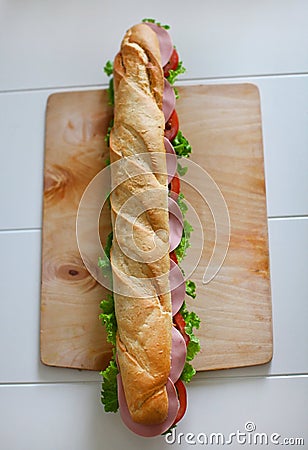 Baguette sandwich with salami, tomatoes and fresh salad