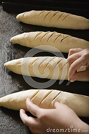 Baker Scoring Loaves Of Bread Dough