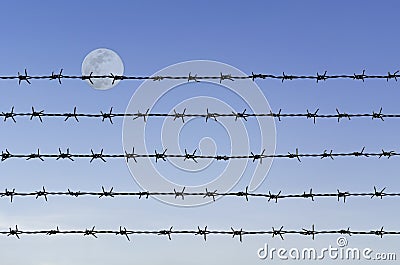Barbed wire over abstract full moon sky