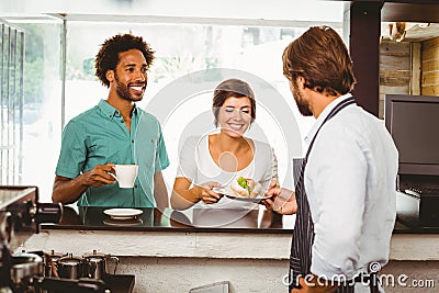 Barista serving two happy customers