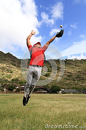 Baseball player jumps high to catch the ball