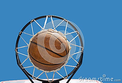 Basketball in the net against clear blue skies
