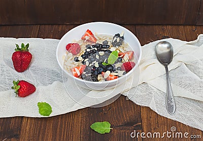 A bawl of oat porridge with fresh berries, honey, almond petals