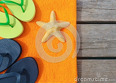 Beach slippers, towel and starfish on wood background. Concept of leisure and travel