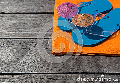 Beach slippers, towel on wood background. Concept of leisure