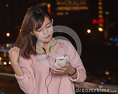 Beautiful Asian woman with smart phone and yellow headphones