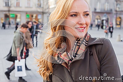 Beautiful blonde happy woman walking on the street in city. Outd